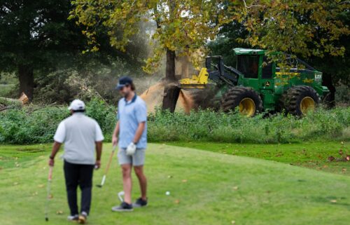 Crews cut down trees on East Potomac Golf Course as golfers continue to use the course in Washington